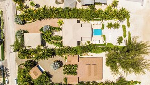 Luchtbeeld van een resort met meerdere gebouwen, palmbomen en een zwembad.