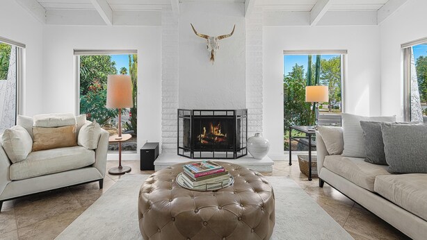 A living room with a fireplace, a sofa, a coffee table, and a bull skull decoration. - Palm Desert Oasis - 3 Bed 2 Bath Home (Palm Desert)