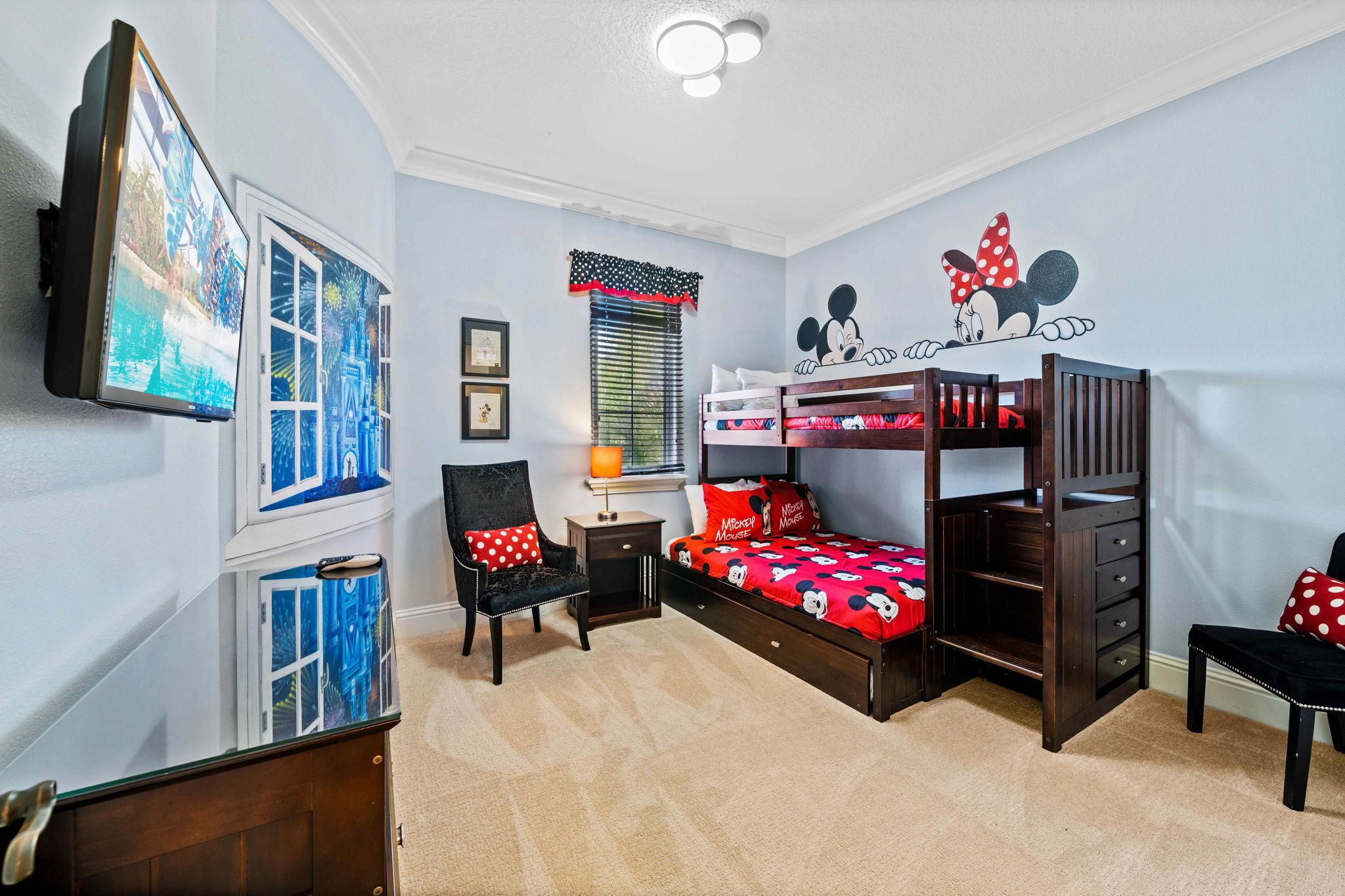 A child's bedroom with bunk beds, a Mickey Mouse wall decal, a TV, and a window with blinds.