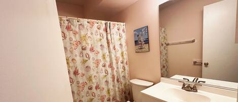 A bathroom with a toilet, sink, and shower curtain.