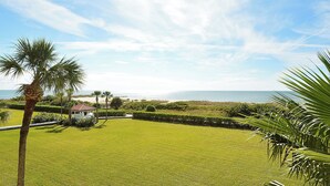 A well-maintained lawn with a small building, palm trees, and a view of the ocean. - Land's End 306 building 8 Beach front corner condo, completely updated (Treasure Island)