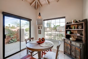 Un comedor con una mesa redonda, sillas, una lámpara colgante decorativa y vistas amplias por ventanas grandes.