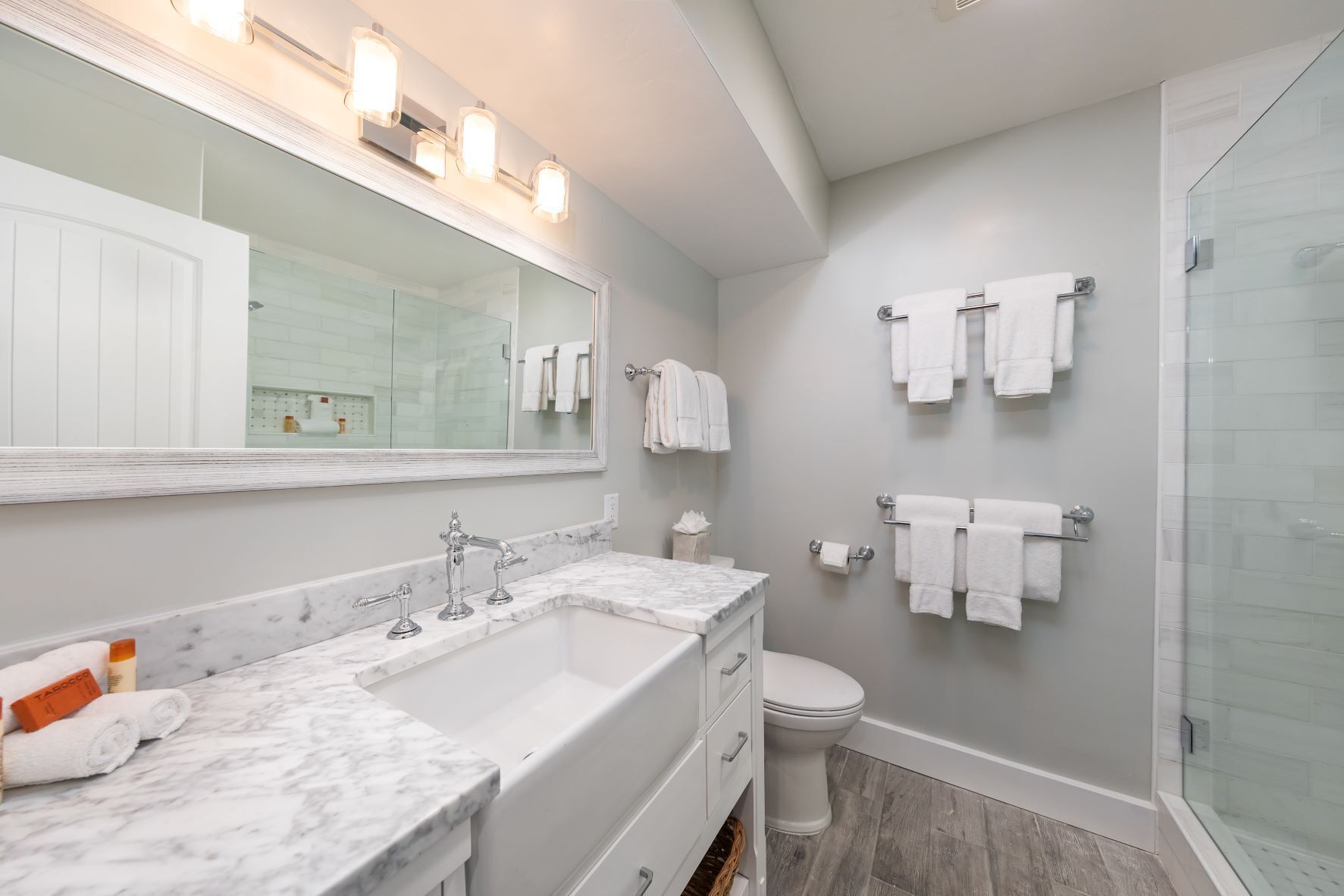 A modern bathroom with a large mirror, a double sink, and a glass shower enclosure.
