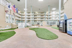Ein mehrgeschossiges Hotel-Atrium mit einer zentralen Laufbahn, Zimmerpflanzen und Verkaufsautomaten.