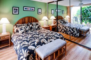 Hotellihuone, jossa on suuri sänky, kaksi yöpöytää, penkki ja suuri peili, joka heijastaa huonetta.