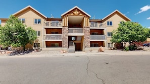 A multi-story hotel with balconies, a central entrance, and a parking area.