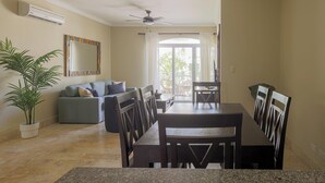 A dining area with a table and chairs, a ceiling fan, a potted plant, and a sofa with cushions. - Beach Residency B2_200Mbps_Pool_Walk2Beach! (Bavaro-Punta Cana)