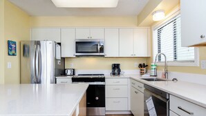 A modern kitchen with white cabinets, stainless steel appliances, and a large island.