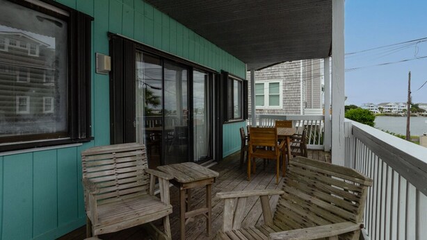 A wooden deck with a table and chairs, a bench, and a view of a body of water.
