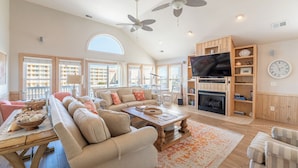 A spacious living room with a large sofa set, a fireplace, a television, and a dining area with a table and chairs.