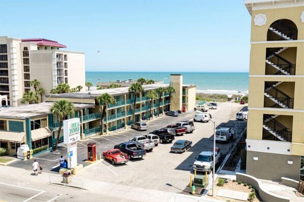 Un hotel de varios pisos con estacionamiento, vista al mar y un letrero para un restaurante.