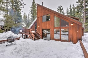 Une cabane moderne en bois, dotée de grandes fenêtres, d’une terrasse et d’un escalier menant à l’entrée.
