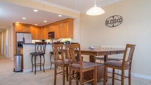 Un comedor con una mesa y sillas de madera, una cocina al fondo y un letrero en la pared que dice 'BLESSED'.