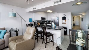 A modern kitchen with white cabinets, stainless steel appliances, and a dining area with a glass table and chairs.