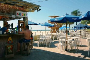 A beachside bar with outdoor seating and umbrellas.