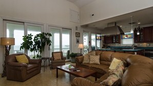 Amplia sala de estar con sofás de cuero, una mesita de centro y un ventanal con vistas a un balcón.