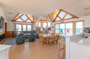 A spacious living area with a dining table, seating, and a view of the beach. - So Good - Corolla, Crown Point, Oceanfront, Ocean View, Pool, Hot Tub, Pool Table (Corolla)