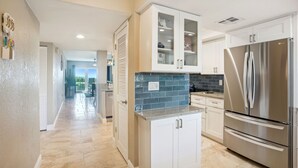 Une cuisine moderne avec des armoires blanches, un réfrigérateur en acier inoxydable et un dosseret de carrelage bleu.
