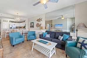 A spacious living area with a large sofa, two armchairs, a coffee table, and a television.