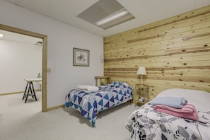 Una habitación con dos camas, un cabecero de madera, un escritorio y un cuadro en la pared.