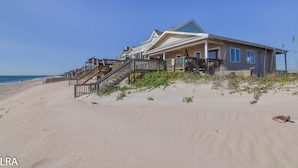 Une maison située en bord de mer, dotée d’une grande véranda, de plusieurs niveaux et offrant une vue sur l’océan.