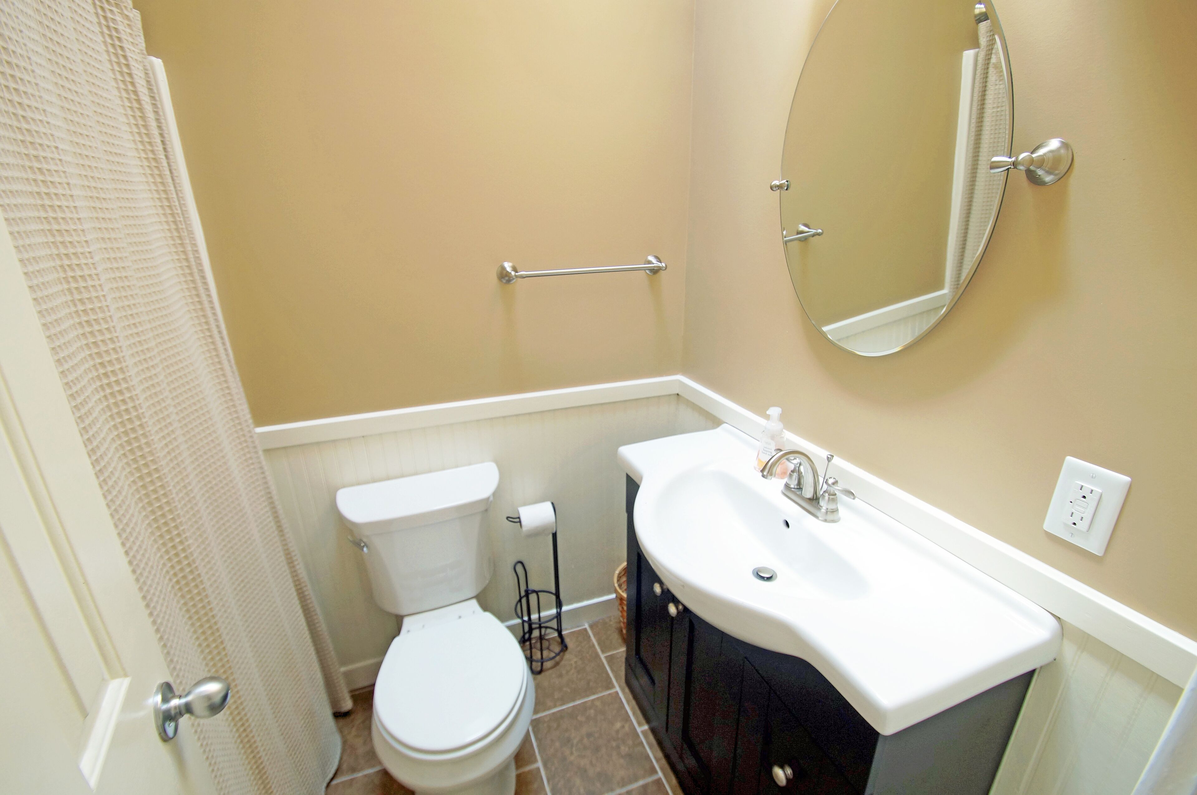 A bathroom with a toilet, sink, and mirror.