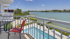 Un balcon avec une piscine, des balustrades blanches et une vue sur une étendue d’eau.