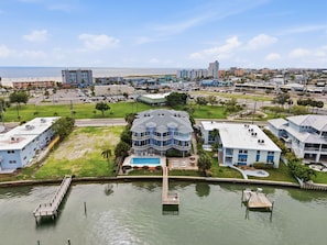 A waterfront hotel with a pool, a dock, and a view of the beach and ocean.
