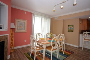 A dining area with a wooden table, white chairs, and a colorful rug.
