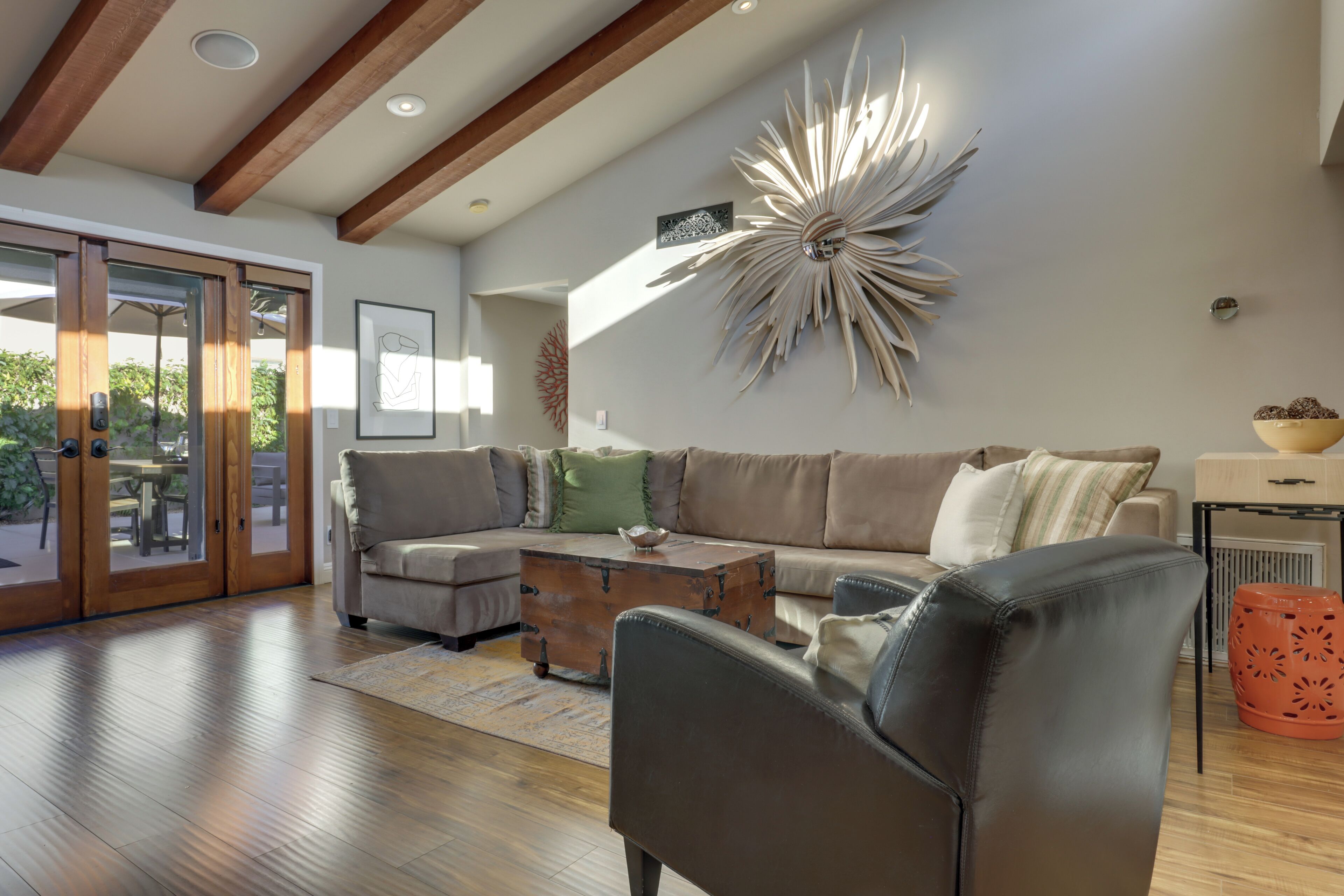 A modern living room with a wooden floor, a large sofa, a coffee table, and a decorative wall piece.