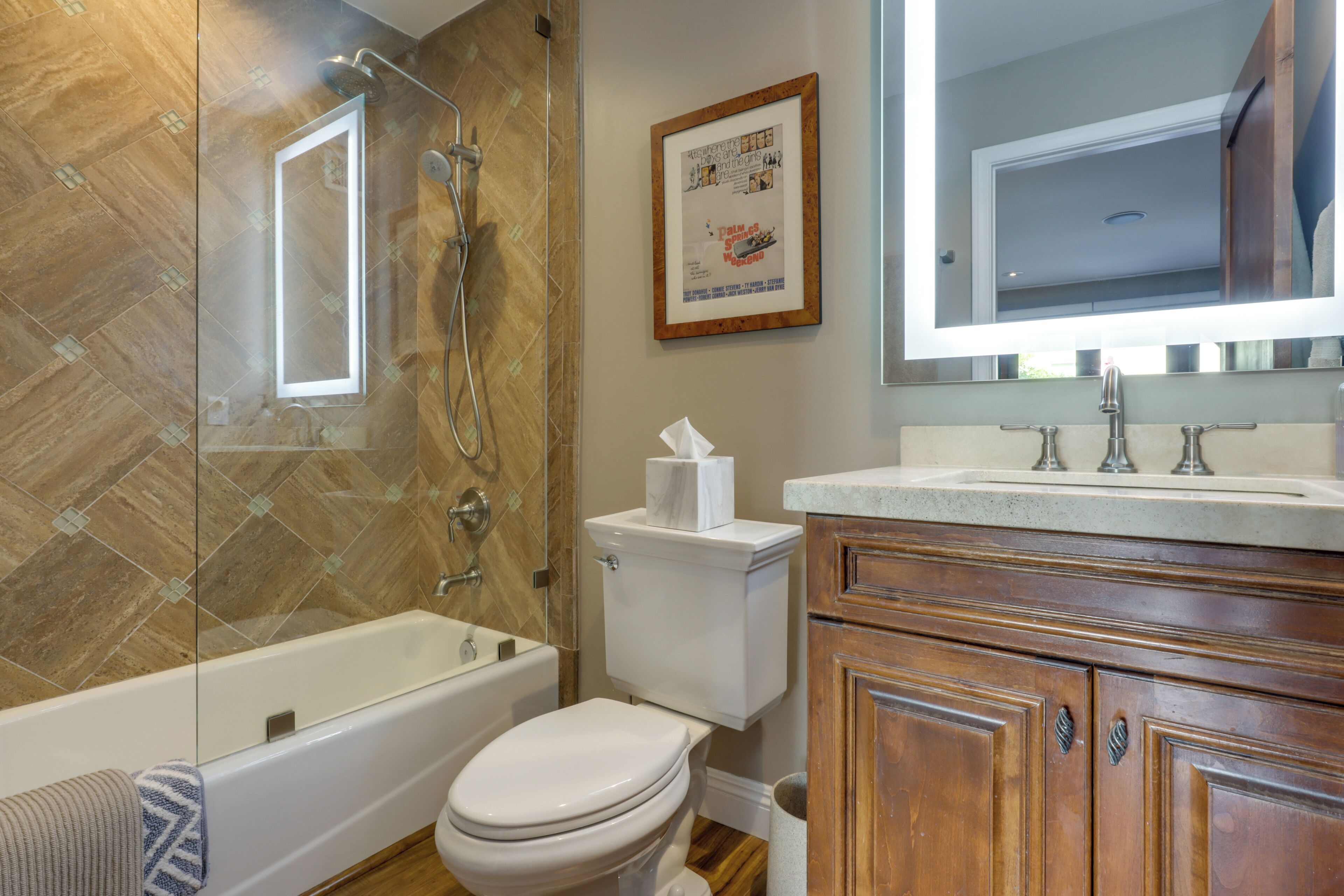A bathroom with a glass-enclosed shower, a toilet, and wooden cabinets.