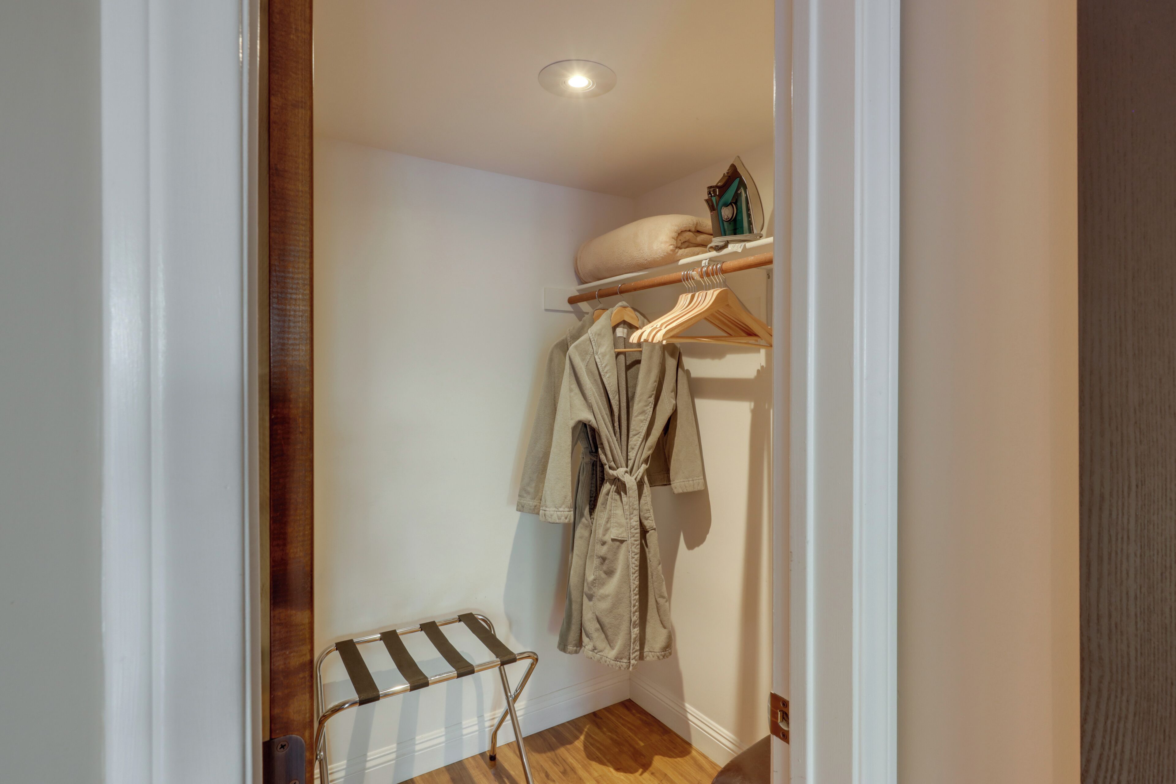 Un petit couloir étroit, doté d’un plancher en bois, d’un radiateur et d’un portant à vêtements sur lequel est suspendue une robe.