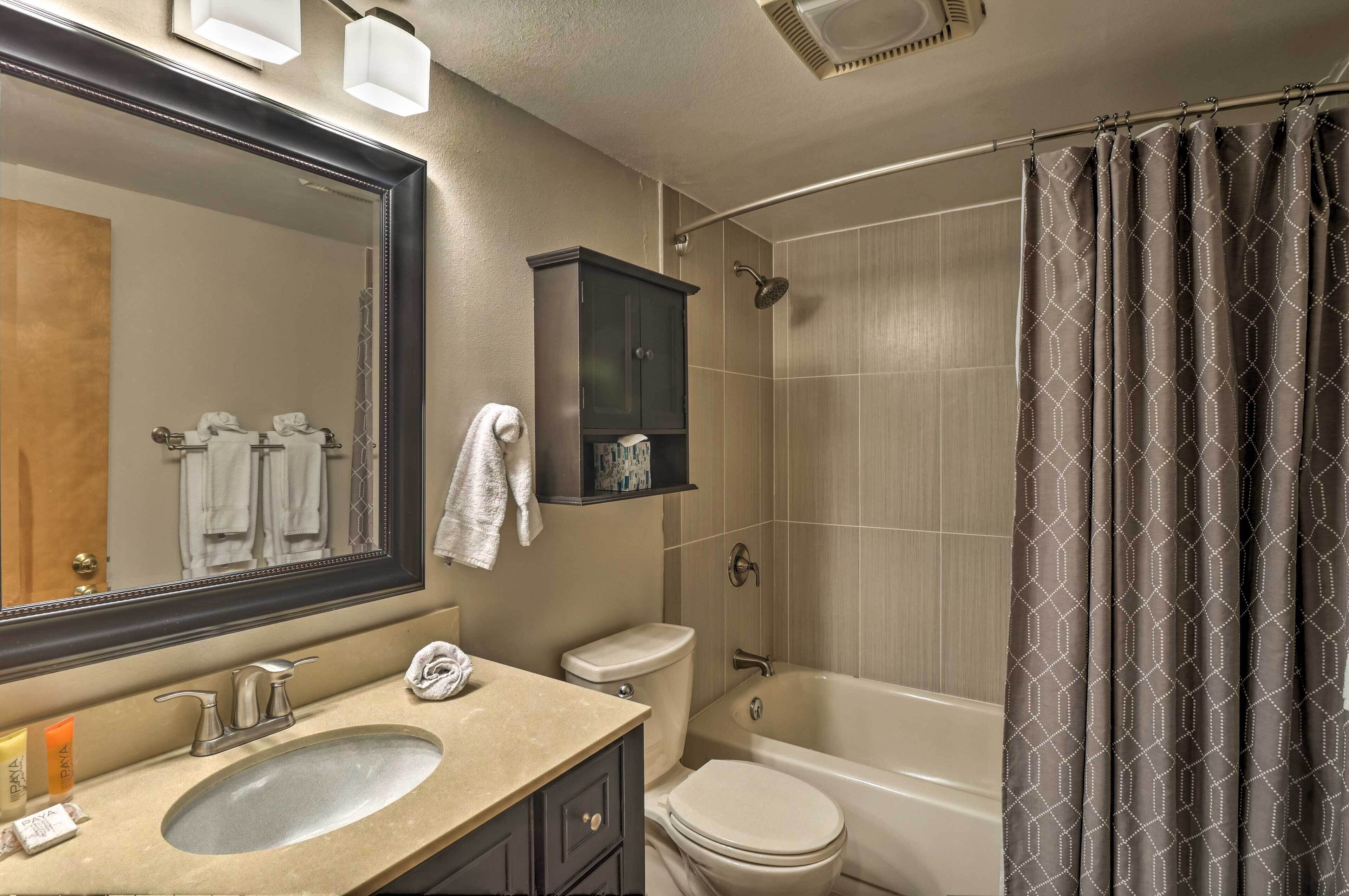 A bathroom with a sink, mirror, cabinet, toilet, and bathtub.