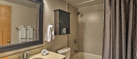 A bathroom with a sink, mirror, cabinet, toilet, and bathtub.