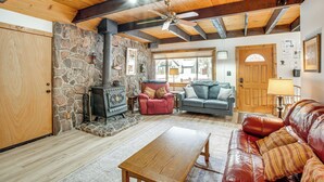 A cozy living room with a stone fireplace, wooden ceiling beams, a leather sofa, and a wooden coffee table. - Discount Available! Lake Tahoe Gem w/ Pool Table (South Lake Tahoe)