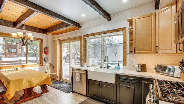A modern kitchen with wooden cabinets, a gas stove, and a dining area with a table and chairs. - Discount Available! Lake Tahoe Gem w/ Pool Table (South Lake Tahoe)