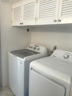 Un espace buanderie équipé de deux machines à laver à chargement frontal et d’un meuble de rangement au-dessus.