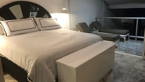 A modern bedroom with a large bed, a bedside table, and a chair.