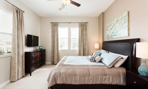 Un dormitorio con cama, televisión, cómoda y ventilador de techo.