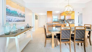 A modern kitchen with a central island, wooden chairs, and a dining table. - Gorgeous Oceanfront Corner Unit Condo w/ Dual Balconies & Panoramic Views! 🌴 (Cape Canaveral)