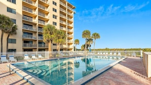 A swimming pool with lounge chairs and a high-rise building with balconies. - Gorgeous Oceanfront Corner Unit Condo w/ Dual Balconies & Panoramic Views! 🌴 (Cape Canaveral)