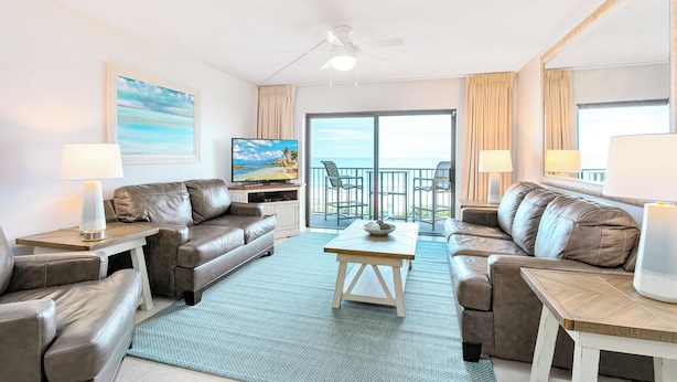 A modern living room with leather sofas, a wooden coffee table, and a television. - Gorgeous Oceanfront Corner Unit Condo w/ Dual Balconies & Panoramic Views! 🌴 (Cape Canaveral)