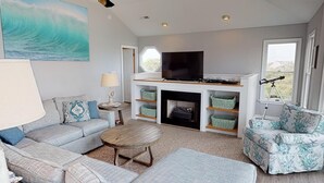 A living room with a sofa, a coffee table, a fireplace, a TV, and a telescope.