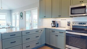 A modern kitchen with light blue cabinets, a stainless steel microwave, and a built-in oven.
