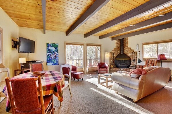 A cozy living room with a fireplace, wooden ceiling beams, and a large window. - 2 Mi to Slopes: Mtn-View Breckenridge Getaway! (Breckenridge)