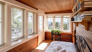 Ein Schlafzimmer mit einem großen Bett, Holzwänden, einer Bücherwand und Meerblick.