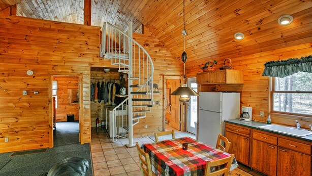 L’intérieur de la cabane est en bois et comprend un coin repas avec une table et des chaises, une cuisine équipée d’un réfrigérateur et d’un évier, ainsi qu’un escalier en colimaçon.