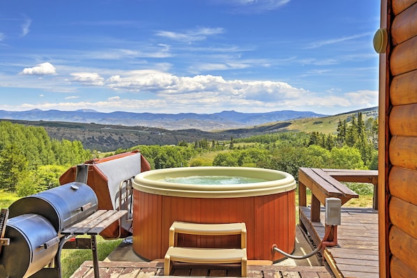 A hot tub on a wooden deck with a mountain view.