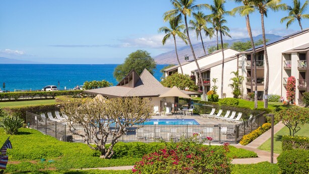 Un resort con piscina, palmeras y vista al océano.