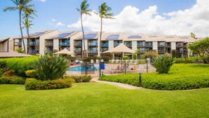 Un hotel con varias plantas, piscina y palmeras.